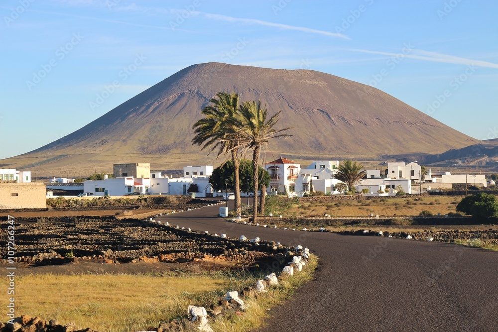 Fototapeta premium Village and volcano in early morning light. Lanzarote, San Canary Islands, Spain. In the inland near San Bartolome and La Geria.