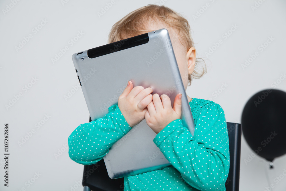 Infant child baby girl toddler sitting and typing digital tablet mobile computer isolated on a white background