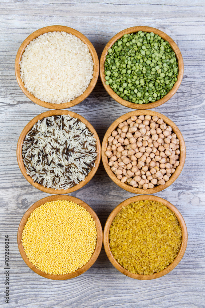 Set of cereals, peas, rice, millet, chickpeas sprinkled in bamboo bowls on wooden background Set of cereals, peas, rice, millet, chickpeas sprinkled in bamboo bowls on wooden background