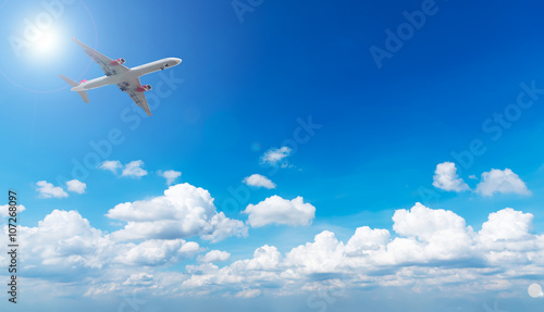 Airplane in blue sky with clouds and sun light, travel concept.