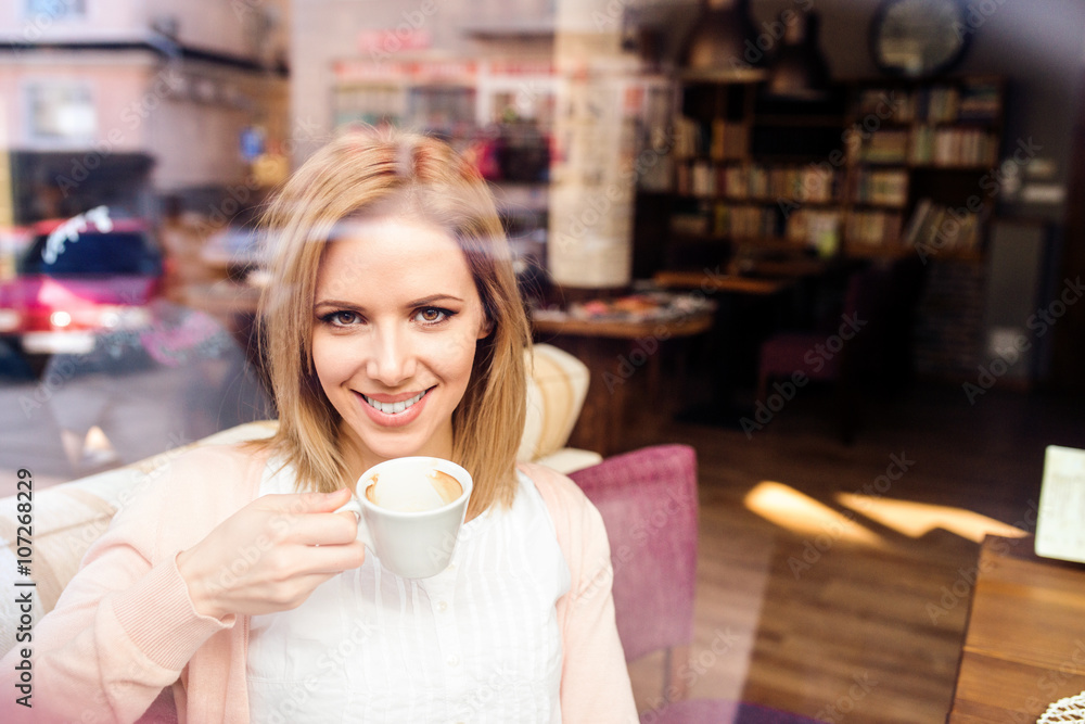 Woman in cafe drinking coffee, street reflection in window Woman in cafe drinking coffee, street reflection in window
