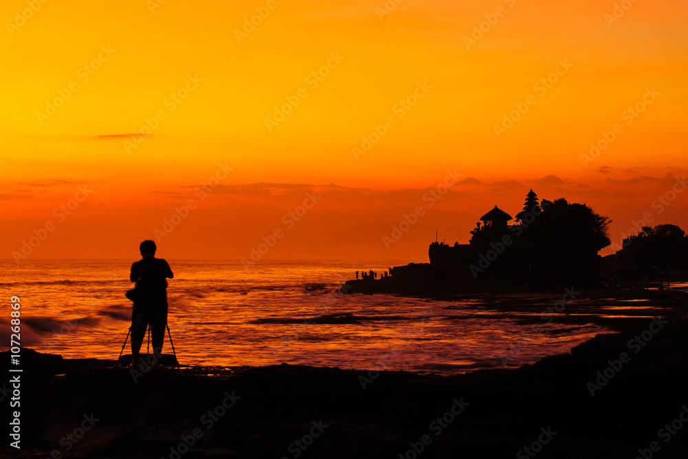 Silhouetted of photographer and Tanah Lot at sunset, Bali, Indon Silhouetted of photographer and Tanah Lot at sunset, Bali, Indon