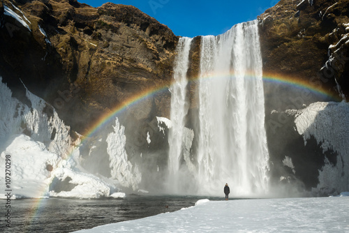 Winter landscape, tourist by famous Skogafoss waterfall with rainbow, Iceland photo