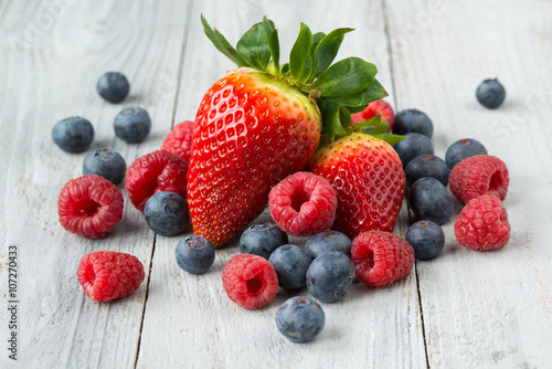 Assorted fresh juicy berries on grey wooden background