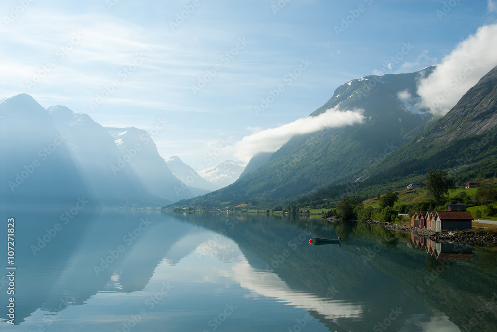 Landscape with mountains reflecting in the lake and small boat near the shore, Norway
