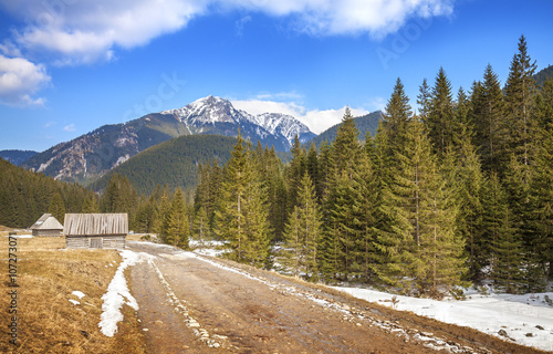 Wooden huts by a dirt road in Tatra Mountains, end of winter and beginning of spring, Poland.