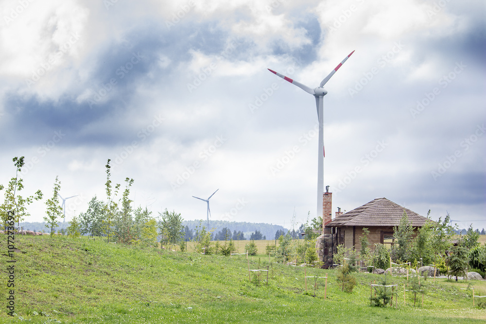 Wind turbines in a country side with a barn and a garden nearby