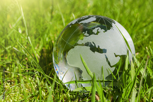 Weltkugel aus Glas, Erde mit Gras und Sonne, Naturschutz, Umweltschutz, Klimaschutz photo