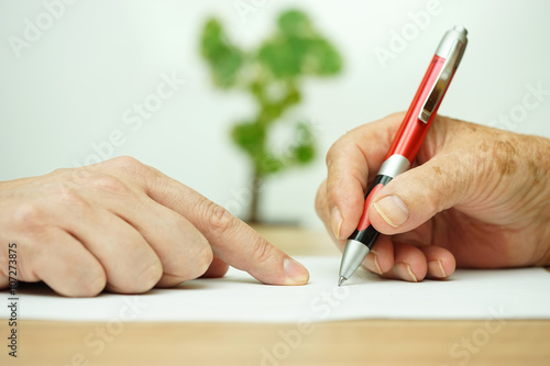 Hand of young adult pointing  elderly person where to sign