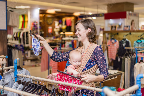 Young woman with baby in a sling in shopping centre