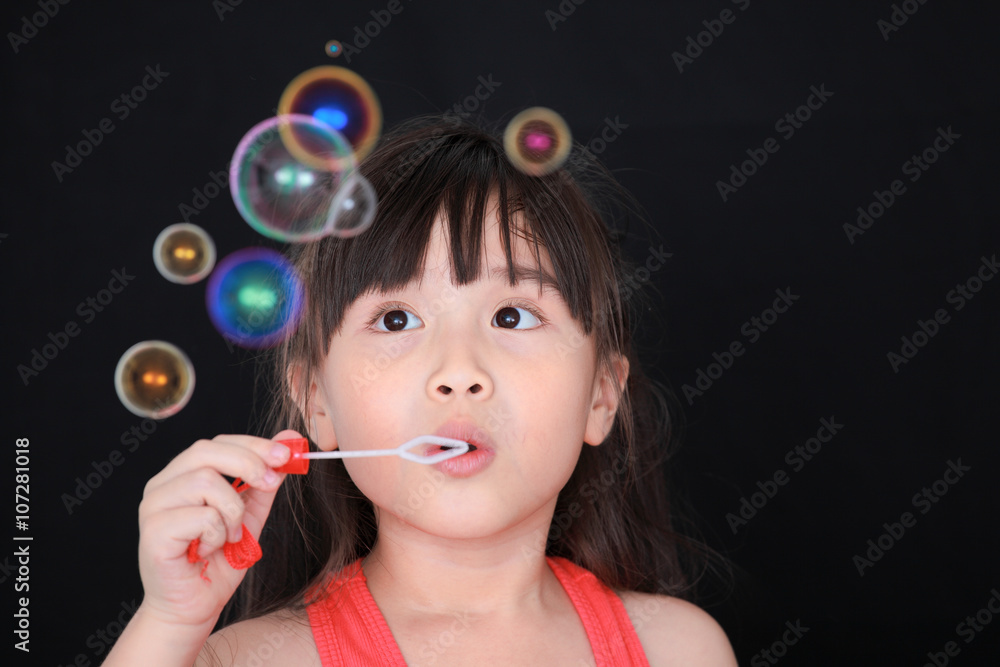 Happy girl play with soap bubbles isolated black background Happy girl play with soap bubbles isolated black background