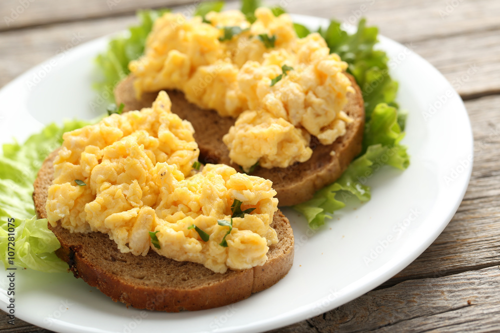 Scrambled eggs with bread and vegetables on a grey wooden table Scrambled eggs with bread and vegetables on a grey wooden table