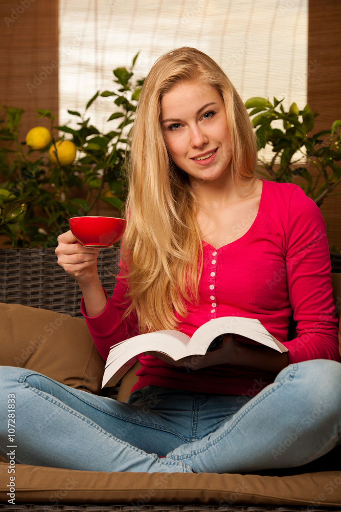 Woman comfortable sitting on sofa, reading book and drinking tea Woman comfortable sitting on sofa, reading book and drinking tea