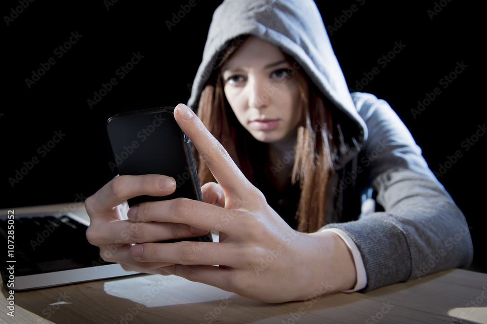 teenager hacker girl in hood using mobile phone in internet cyber crime expert or cybercrime teenager hacker girl in hood using mobile phone in internet cyber crime expert or cybercrime