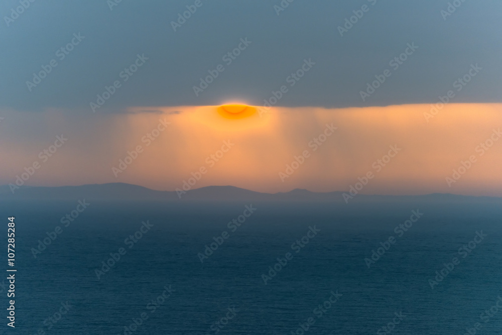 Amazing sunrise above the sea through a cloudy sky. A magnificen