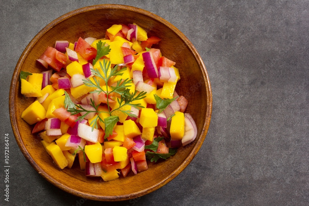 Homemade Mango salsa served in a wooden plate top view Homemade Mango salsa served in a wooden plate top view