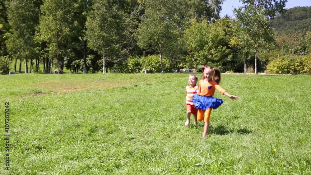 Happy girl and boy running on the grass in the park. Brother and sister. Happy girl and boy running on the grass in the park. Brother and sister.