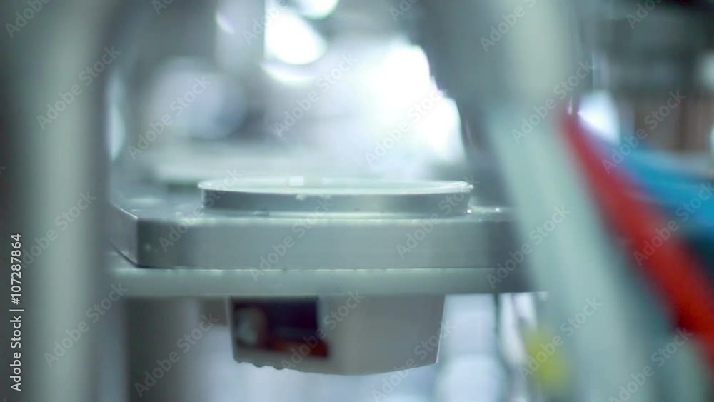 Food packaging line/Yogurt pouring in plastic package at dairy factory/Food production line at dairy plant/Plastic container on production line/Food technology/Food manufacturing process Food packaging line/Yogurt pouring in plastic package at dairy factory/Food production line at dairy plant/Plastic container on production line/Food technology/Food manufacturing process