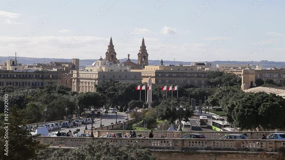 Pedestrians and vehicles move towards the War Memorial and the Church of St. Publius, as Malta flags fly,
in Malta's Capital of Valetta on 18 January, 2016. Pedestrians and vehicles move towards the War Memorial and the Church of St. Publius, as Malta flags fly,
in Malta's Capital of Valetta on 18 January, 2016.