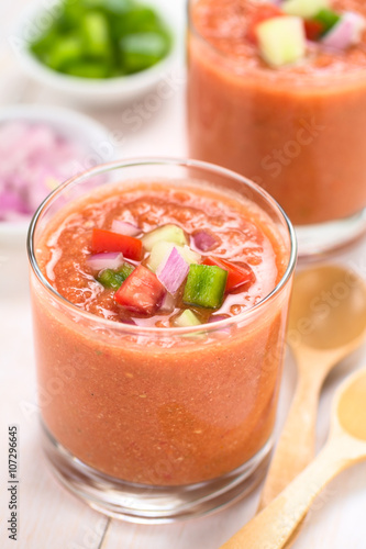 Traditional Spanish cold vegetable soup Gazpacho made of tomato, cucumber, bell pepper, onion, garlic and olive oil (Selective Focus, Focus on the front of vegetables on top of the soup)