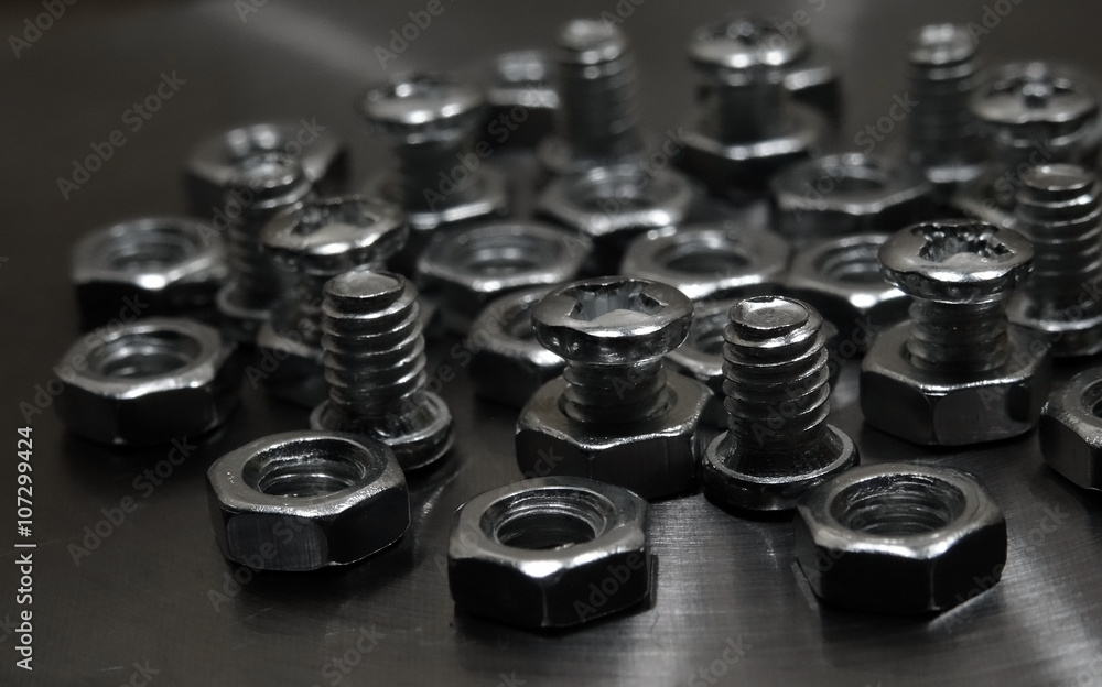 Screw bolts and hex nuts on aluminium surface closeup shot Screw bolts and hex nuts on aluminium surface closeup shot