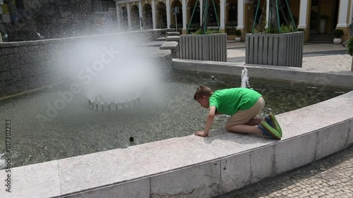 European boy washes in a city fountain in the center of Macao photo