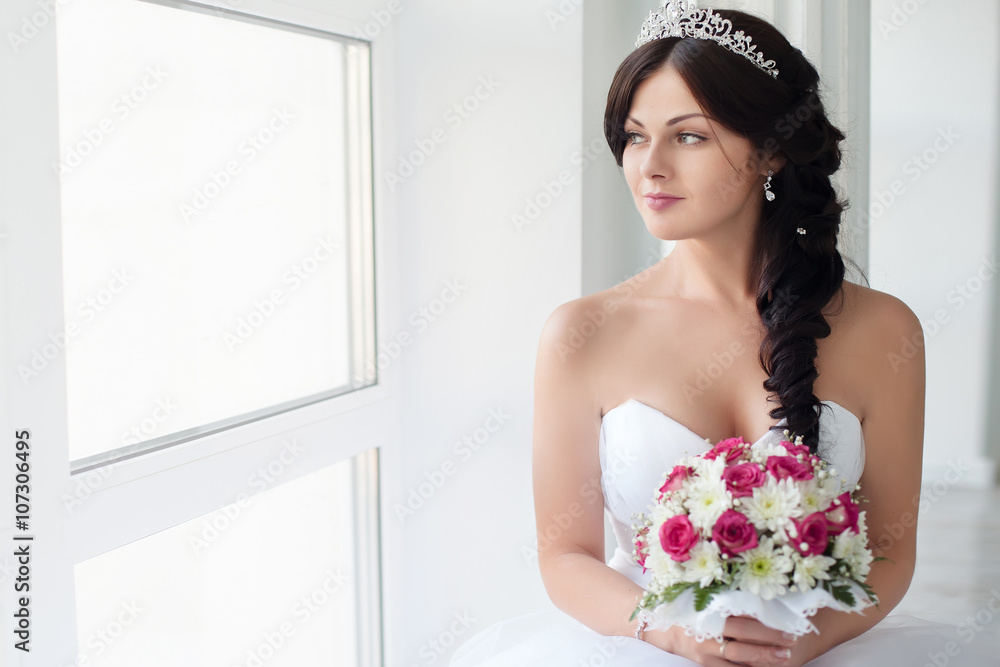 Beautiful brunette bride in a wedding dress and a crown on her head. Beauty face.