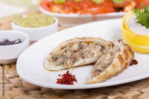 Plate of stuffed cuttlefish inside cheese, mushroom and seafood serving with aubergine salad