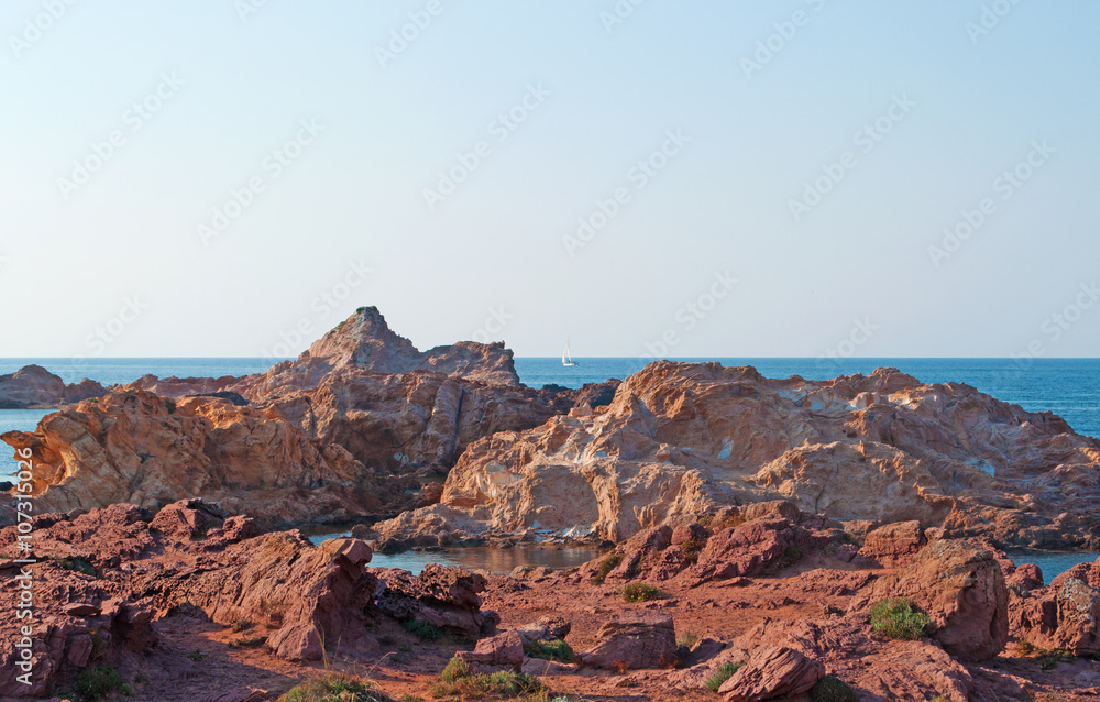 Naklejka premium Minorca, isole Baleari, Spagna: sabbia rossa e rocce sul sentiero per Cala Pregonda, la baia simile al pianeta Marte, il 15 luglio 2013