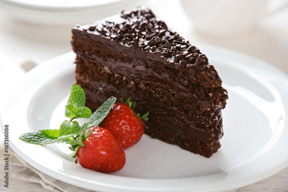 Chocolate cake with chocolate cream and fresh berries on plate, on light background Chocolate cake with chocolate cream and fresh berries on plate, on light background