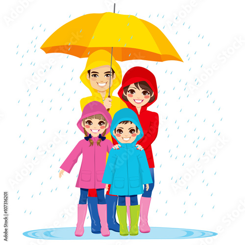Happy family with raincoats under big umbrella on rainy day