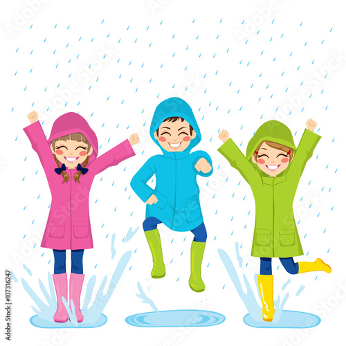 Little kids playing on puddles wearing colorful raincoats and boots