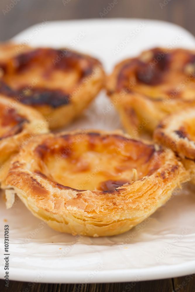 portuguese dessert pasteis de nata on white dish on brown wooden background portuguese dessert pasteis de nata on white dish on brown wooden background