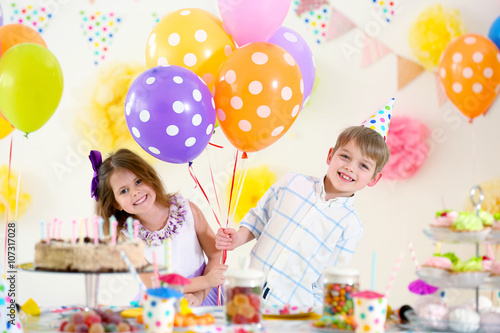 Happy little girl and boy with balloons having fun at birthday party