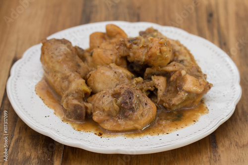 boiled chicken with beer sauce in white plate on brown wooden background