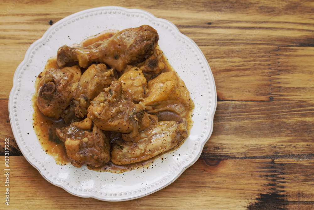 boiled chicken with beer sauce in white plate on brown background