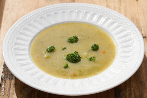 vegetable soup with broccoli on white dish on brown wooden background