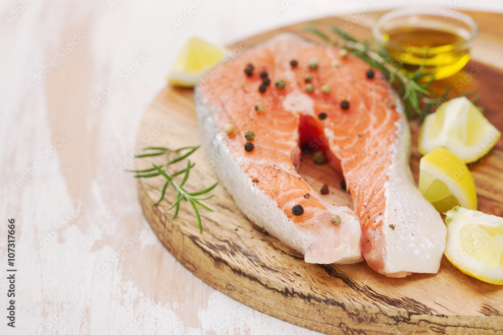 fresh salmon with lemon and rosemary on wooden board on white background fresh salmon with lemon and rosemary on wooden board on white background