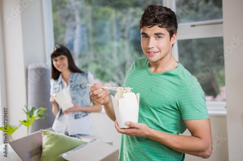 Young man and woman eating noodles at home