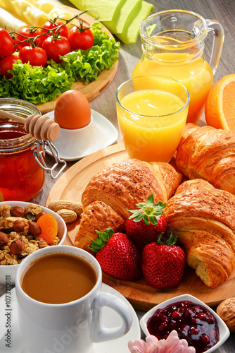 Breakfast consisting of croissants, coffee, fruits, orange juice