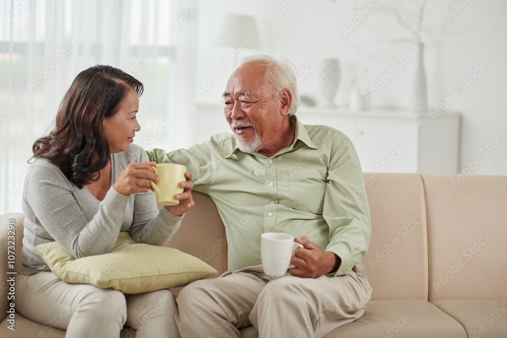 Asian aged couple drinking tea and chatting at home