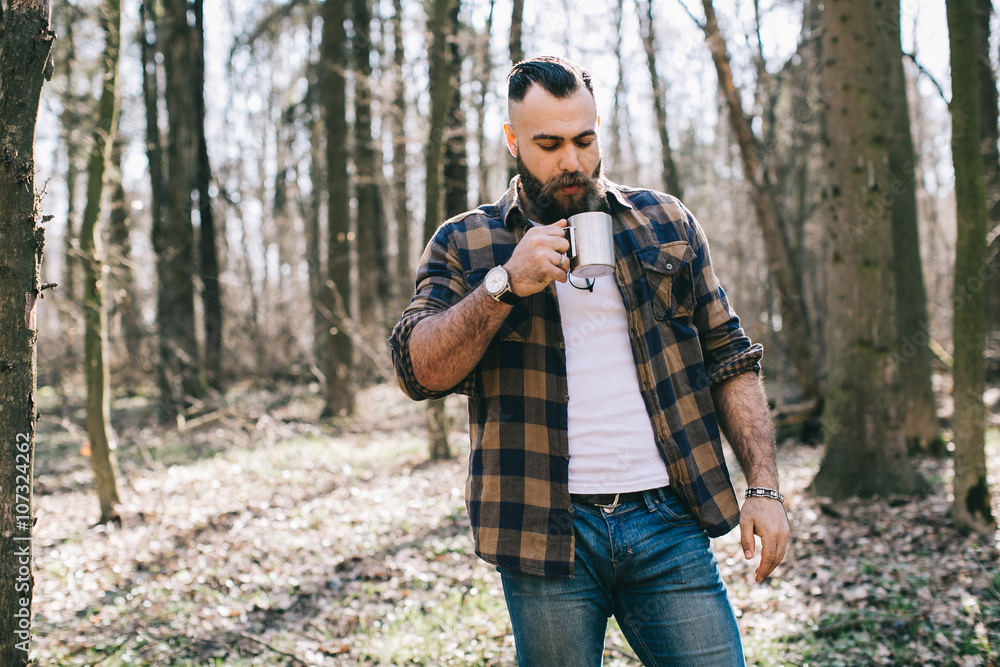 Bearded man drinking coffee in the wood
