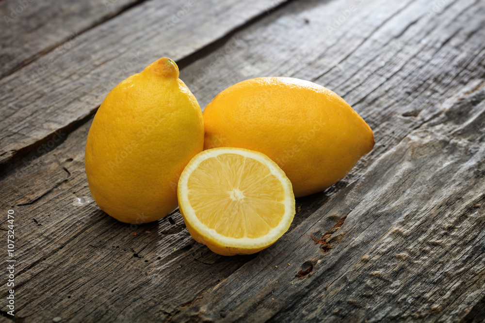 Two lemons and one half, on wooden surface