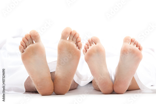 woman and man feet in bed isolated on white