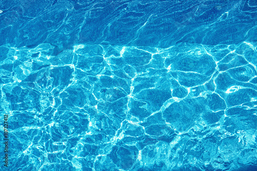 Water Background. Shining Blue Ripped Water Surface In Hotel Swimming Pool With Bright Sunny, Sun Light Reflections. Liquid Texture. Summertime. Summer Holidays Vacation Concept.