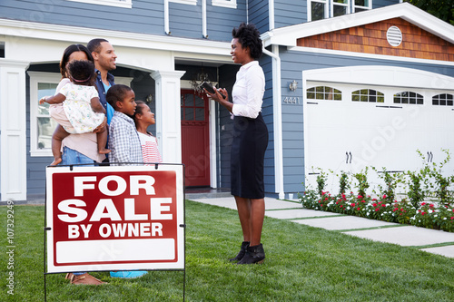 Foto Estate agent and family outside house with a ‘for sale’ sign