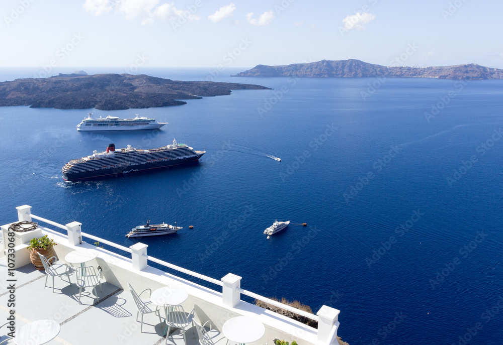  Restaurant terrace with view at sea and cruise ships. White architecture of Santorini