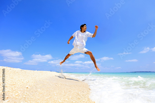 南国の美しいビーチを走る笑顔の男性