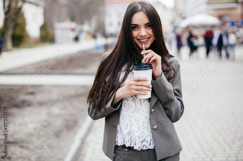 Beautiful business woman drinks coffee on a street