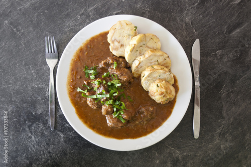 Czech traditional recipe for beef goulash with homemade dumpligs, served in simple rustic style photo